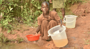 M&auml;dchen sch&ouml;pft Wasser aus einer offenen Wasserstelle in Malawi