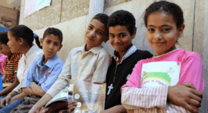 schulkinder-mit-buechern-oberaegypten Schülerinnen und Schüler sitzen mit ihren Schulbüchern vor der AUEED-Schule in Oberägypten.